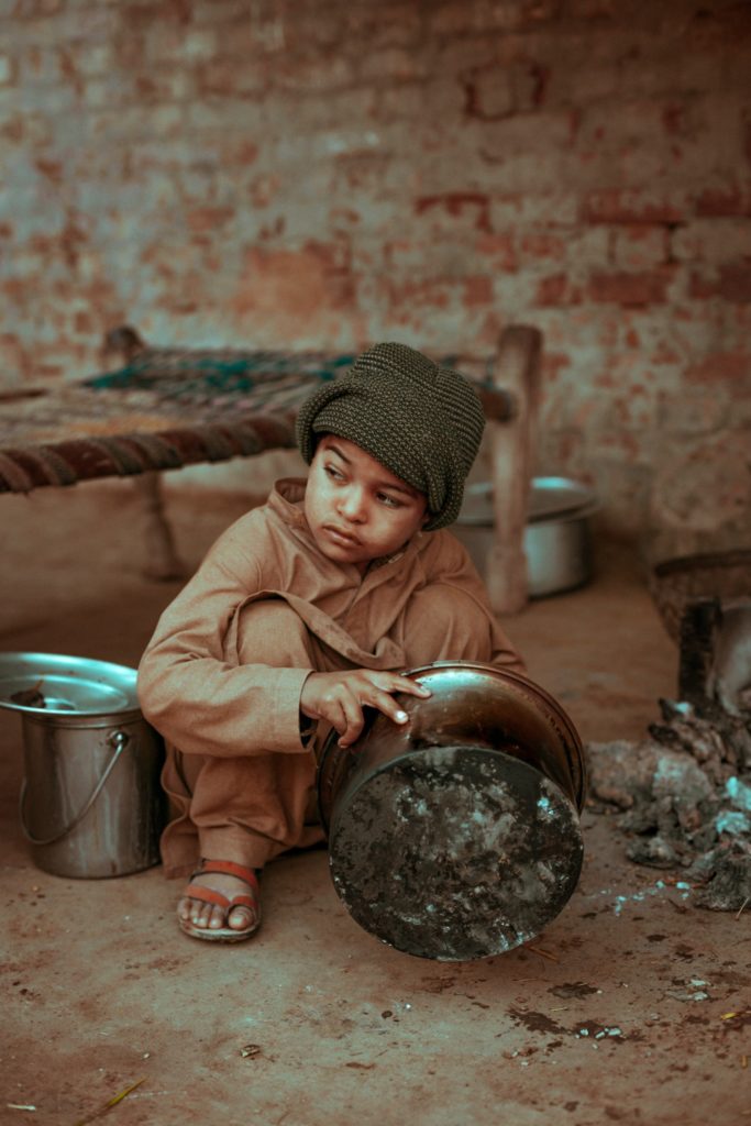 A young boy looking through an empty pot for food